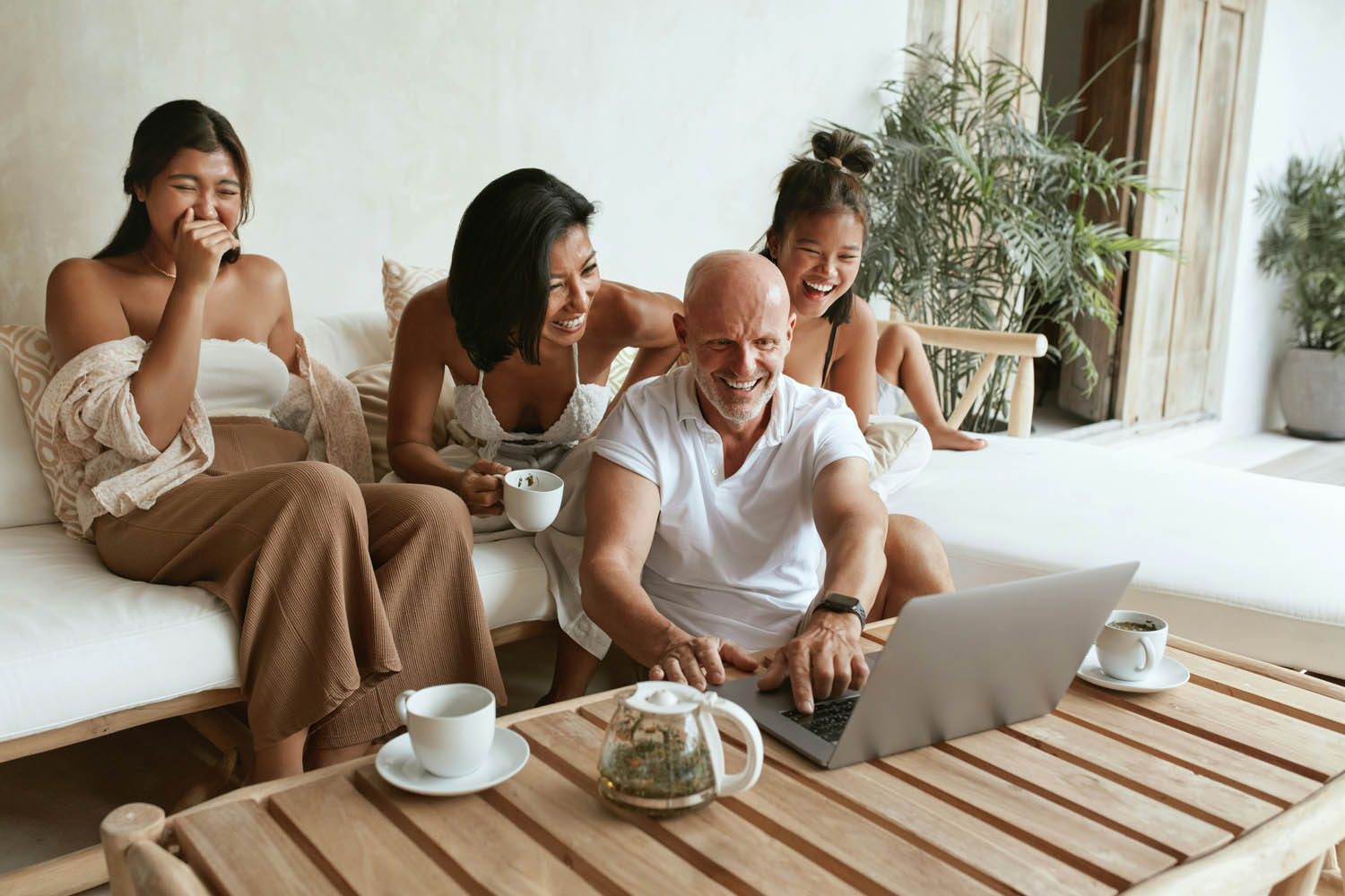 Group of friends planning a holiday together on a laptop at a luxury villa